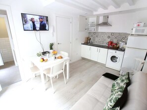 A compact living space with a dining area, kitchenette, and a sofa.