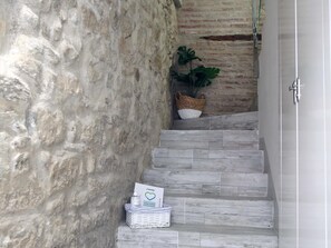 A staircase with stone walls, a plant, and a basket.