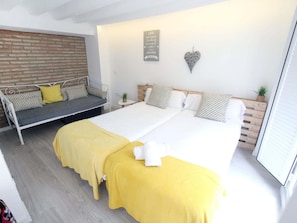 A modern bedroom with a bed, a sofa, a small table, and a wall-mounted heart decoration.