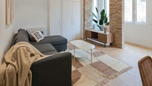 Una sala de estar moderna con un sofá, una mesa de centro, un aparador y un ventanal grande.