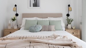 Een netjes ingerichte slaapkamer met een bed, nachtkastjes, een wandlamp en een ingelijst schilderij.