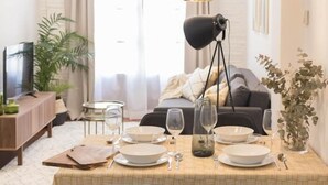 A dining table set with plates, glasses, and cutlery, a lamp, and a sofa in the background. - Los apartamentos de Elena, centro histórico I by El Rincon (Logroño)