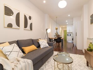 Una sala moderna con un sofá gris, una mesa de centro redonda y una obra de arte abstracta en la pared.