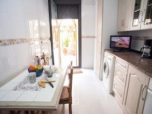 Eine Küche mit Waschmaschine, Fernseher und Essbereich mit Tisch für zwei Personen.