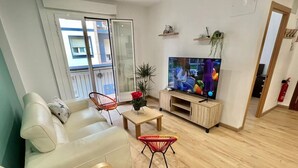 Una sala de estar moderna con sofá, dos sillones, una mesa de centro, televisor y un balcón con vistas.