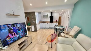 Una sala de estar moderna con televisor, sofá y comedor.