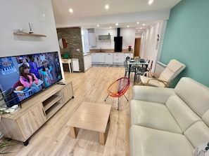 Ein modernes Wohnzimmer mit Fernseher, Sofa und Essbereich.