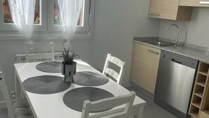 A modern kitchen with a white table, grey placemats, a stainless steel dishwasher, and a window with sheer curtains. - Apartment La Paz, new, wifi & confort by El Rincon (Logroño)