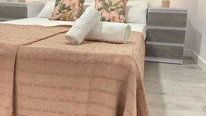 A neatly made bed with a pink blanket and two pillows, a bedside table with a lamp, and a wall-mounted picture frame. - Apartment La Paz, new, wifi & confort by El Rincon (Logroño)