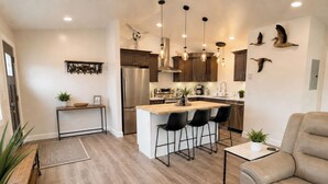 Una cocina moderna con una isla central, taburetes de bar e iluminación colgante.