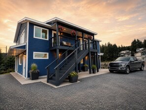 Une maison moderne à deux étages, dotée d’un escalier, d’une allée et d’un camion garé.