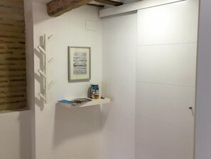 A room with a white door, a framed welcome sign, and a small shelf with items. - Loft Laurel acogedor (Logroño)