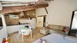 Una stanza compatta con angolo cottura, zona pranzo, divano e letto.