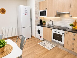 Eine moderne Küche mit Kühlschrank, Mikrowelle, Waschmaschine und Backofen.