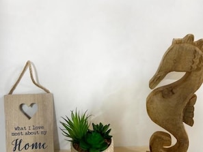 Una escultura de caballot de mar de fusta, un senyal penjant amb una forma de cor i una planta en test.