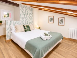 Ein Schlafzimmer mit einem Bett, Kissen, einer grünen Decke und einem zusammengerollten Handtuch.