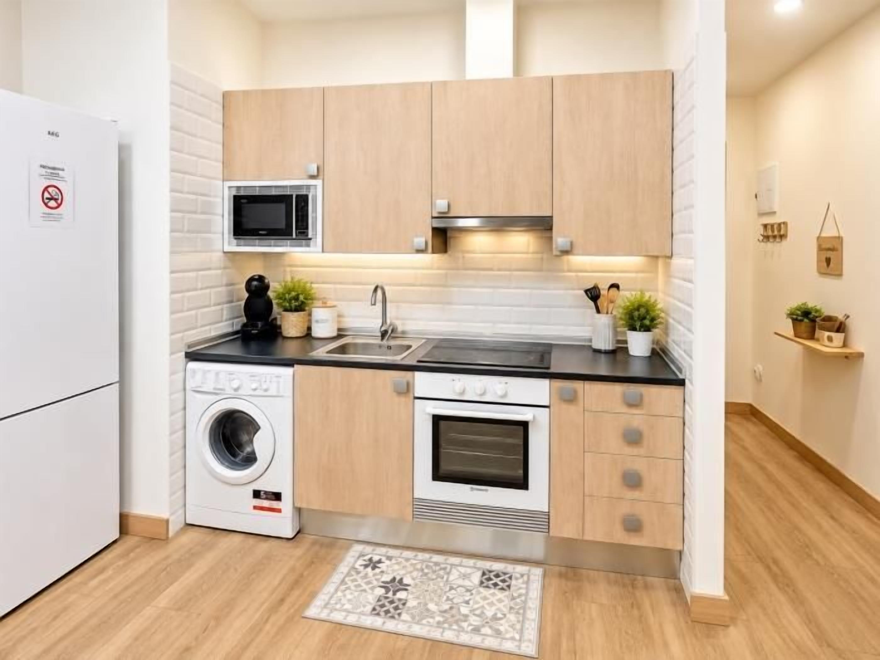 Cocina compacta equipada con lavadora, microondas, horno y lavaplatos.