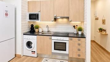 Cocina compacta equipada con lavadora, microondas, horno y lavaplatos.