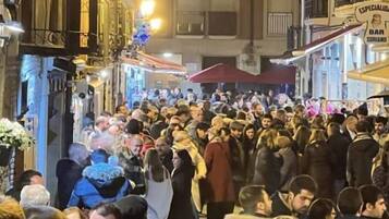 A crowded street scene with people walking and standing.