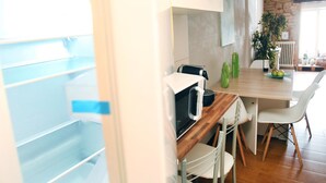A modern kitchen with a wooden countertop, white cabinets, and a dining area with a stone wall and a plant. - RINCON DEL MARQUES ENTRESUELO (Logroño)