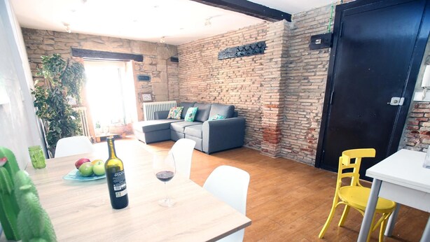 A dining area with a table, chairs, a bottle of wine, and a glass of red wine. - RINCON DEL MARQUES ENTRESUELO (Logroño)