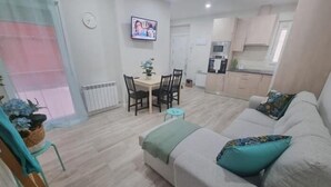 Een woonkamer met een bank, een eettafel en een aan de muur bevestigde televisie.