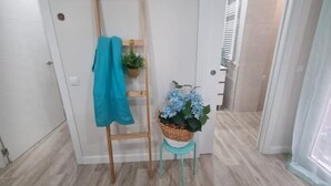 Een gang met een houten ladder die tegen een muur leunt, een mand met een plant, en een blauwe handdoek die aan de ladder hangt.