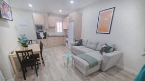 Een knus woongedeelte met een eethoek, kitchenette en een bank.