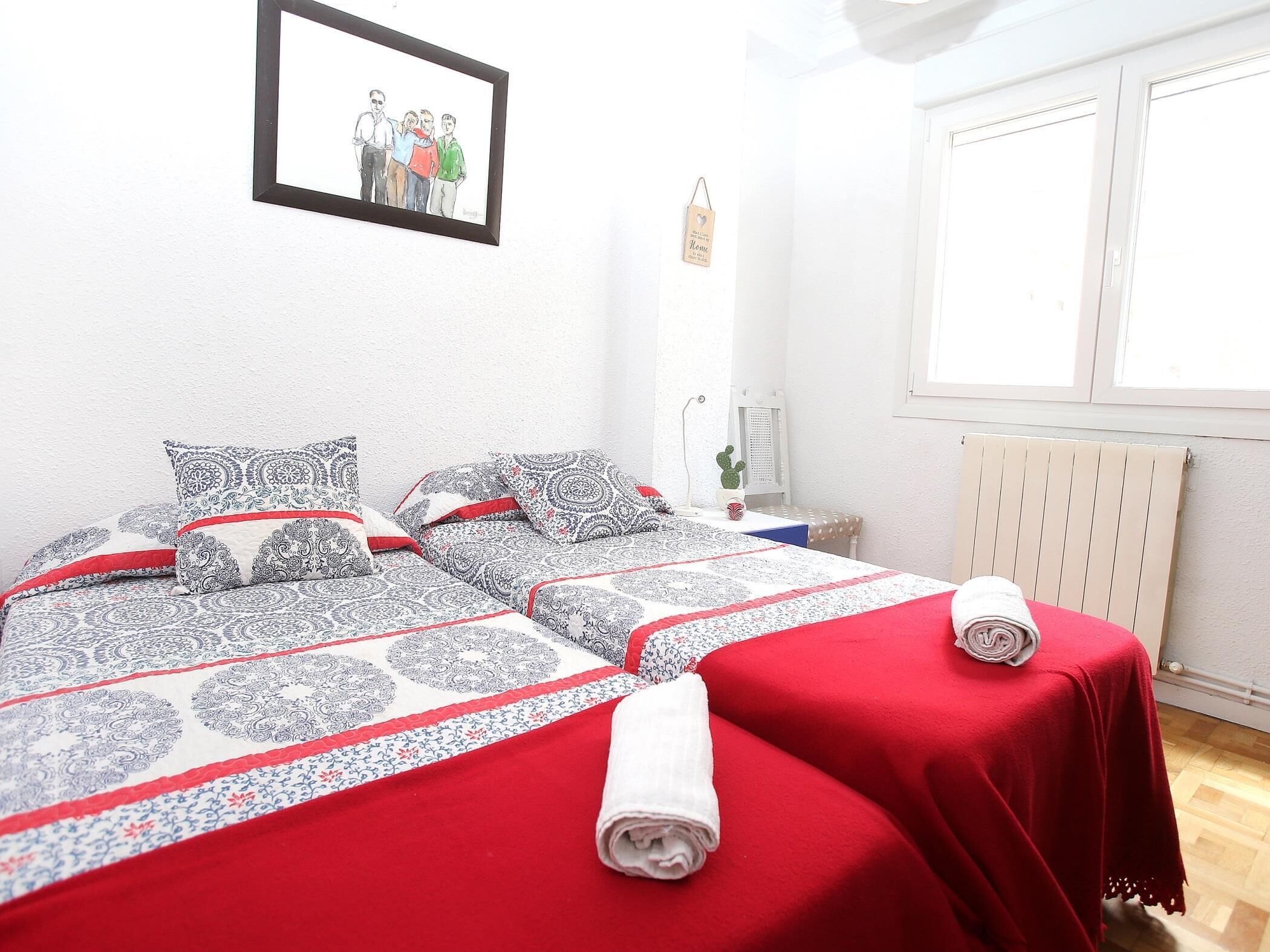 Una camera da letto con due letti, un quadro appeso al muro, un termosifone e una finestra.