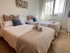 A hotel room with two beds, a wall-mounted towel rack, and a window with patterned curtains. - Pool and Confort by El Rincon (Logroño)