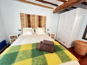 A bedroom with a bed, white nightstands, a wardrobe, and a checkered blanket. - La Redonda. En el corazón de Logroño. Ascensor (Logroño)