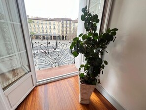 Een balkon met uitzicht op gebouwen, een bloempot en een smeedijzeren hekwerk.