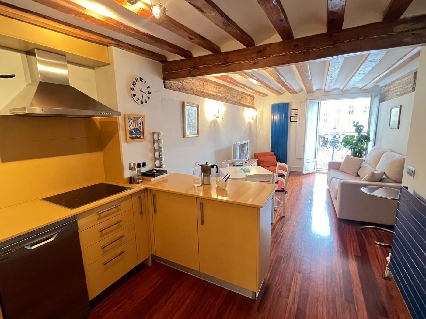 Une cuisine avec des meubles de rangement en bois, une cuisinière et une horloge au mur.