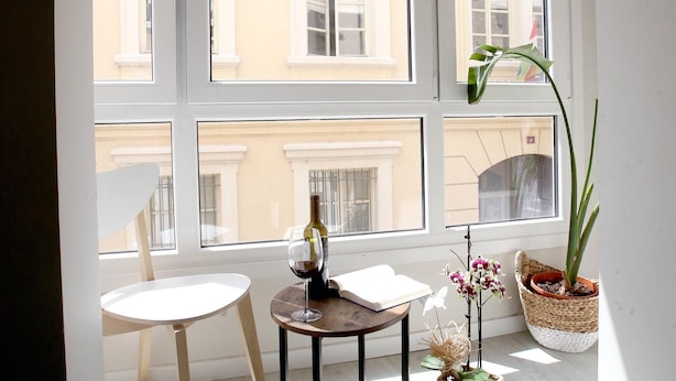 A room with a table, a chair, a potted plant, and a window with a view of buildings. - EL RINCÓN DE LA MERCED I (Logroño)