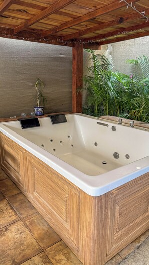 Tinaco rectangular con varios chorros, suelo de madera y una pérgola arriba.