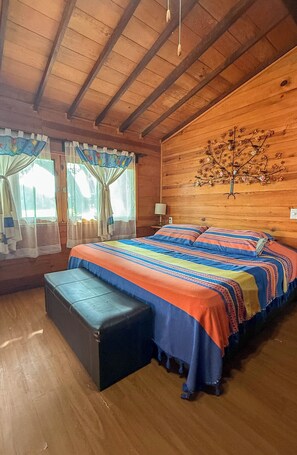 Un dormitorio de cabaña de madera con una cama, un banco y un adorno de árbol colgado en la pared.