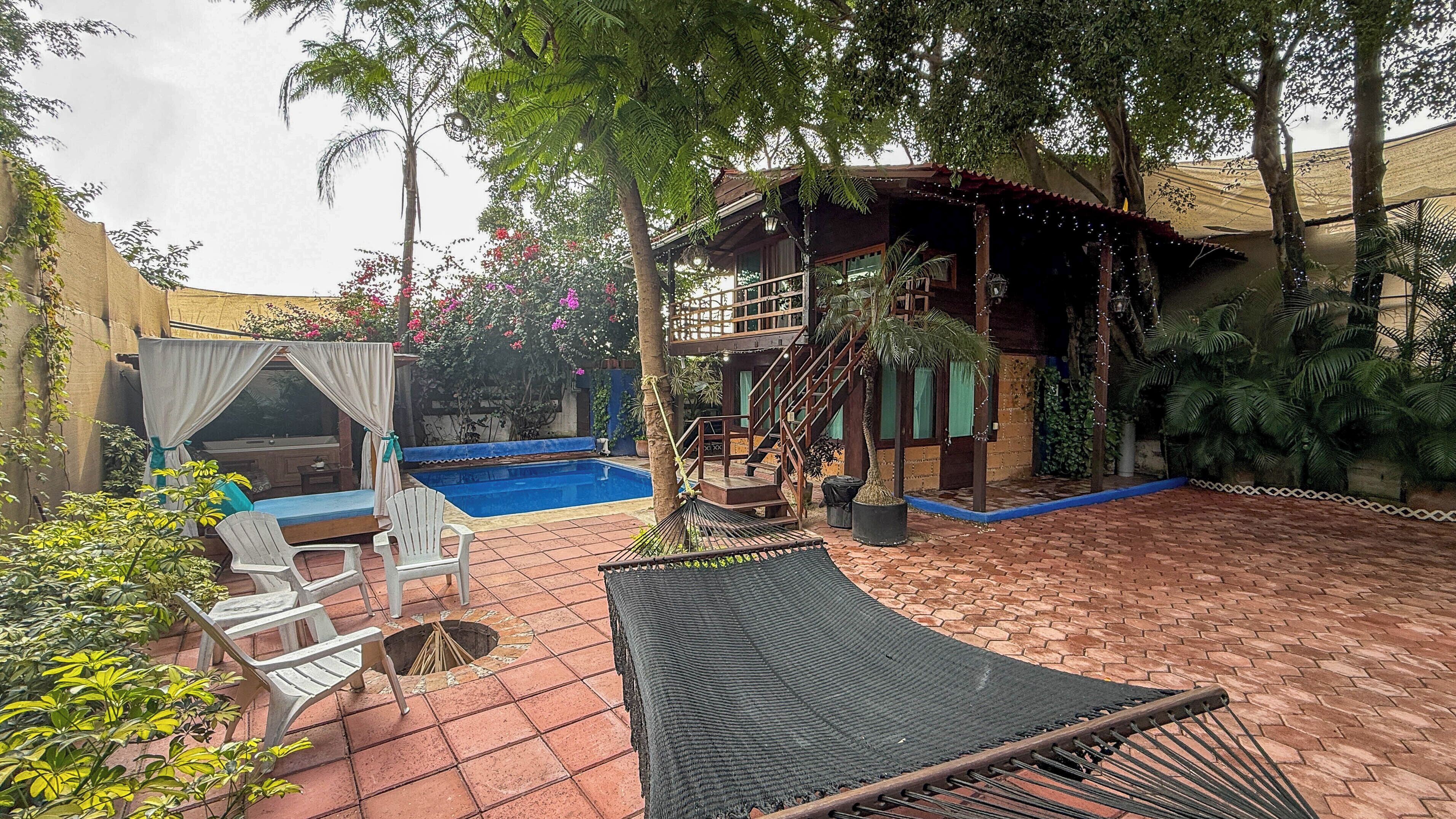 A pool area with a hammock, chairs, and a covered seating area.