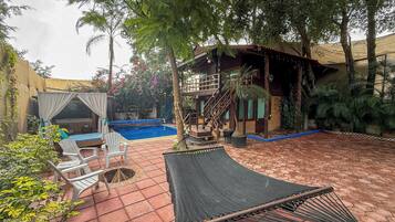 A pool area with a hammock, chairs, and a covered seating area.