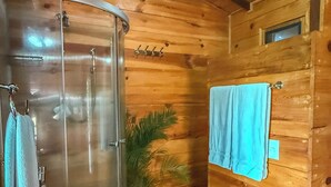 A wooden cabin interior with a glass shower enclosure, a wooden cabinet with a towel, and a potted plant. - La CABAÑA TABACHIN RELAXATION FOR COUPLES JACUZZI & ALBERCA (Yautepec de Zaragoza)