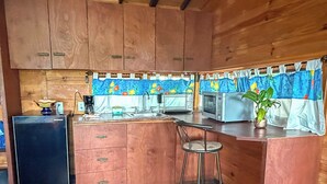 A compact kitchen with wooden cabinets, a sink, a microwave, and a refrigerator. - La CABAÑA TABACHIN RELAXATION FOR COUPLES JACUZZI & ALBERCA (Yautepec de Zaragoza)