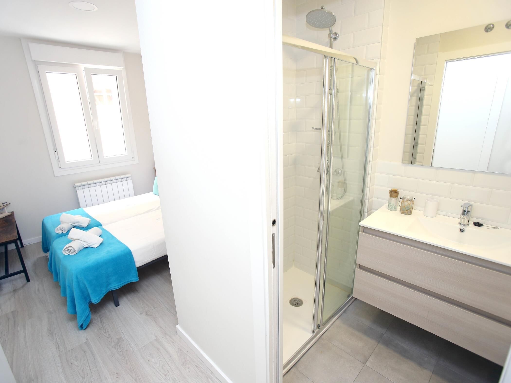 Une chambre d’hôtel comprenant un lit, une salle de bain avec une douche à parois de verre, un lavabo et un miroir.