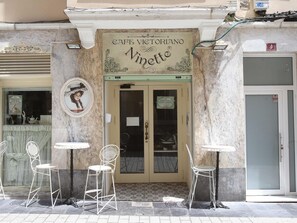 Een café genaamd 'Cafe Vittoriano Ninetta' met terras en een betegelde ingang.