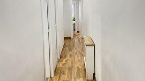 A hallway with white walls, wooden flooring, and recessed ceiling lights. - Rioja Centro 3 habitaciones (Logroño)