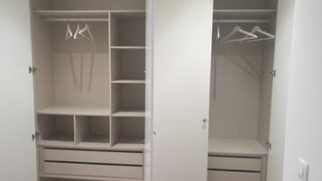 A walk-in closet with multiple shelves, hanging space, and drawers.