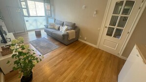 A living room with a grey sofa, a potted plant, and a wooden floor. - Santiago Tower Views (Logroño)