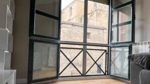 A room with a large window, wooden flooring, and a grey sofa. - Santiago Tower Views (Logroño)