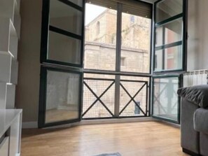 Una habitación con un ventanal grande, suelo de madera y un sofá gris.