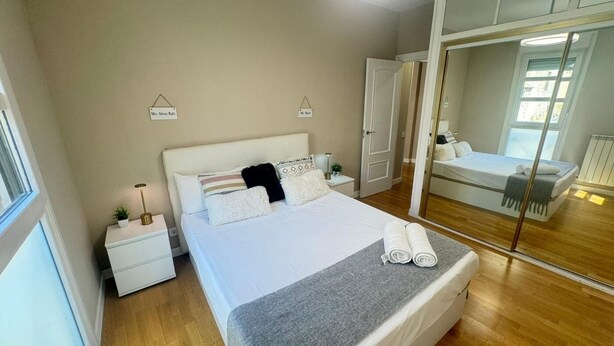 A bedroom with a bed, bedside tables, a mirror, and a wardrobe. - Santiago Tower Views (Logroño)