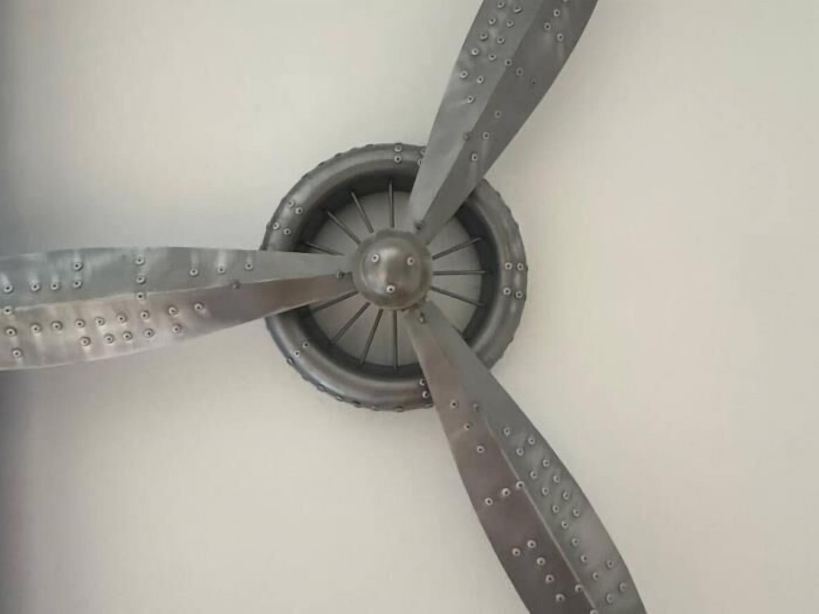 A ceiling fan with four blades, a central hub, and a protective grill.
