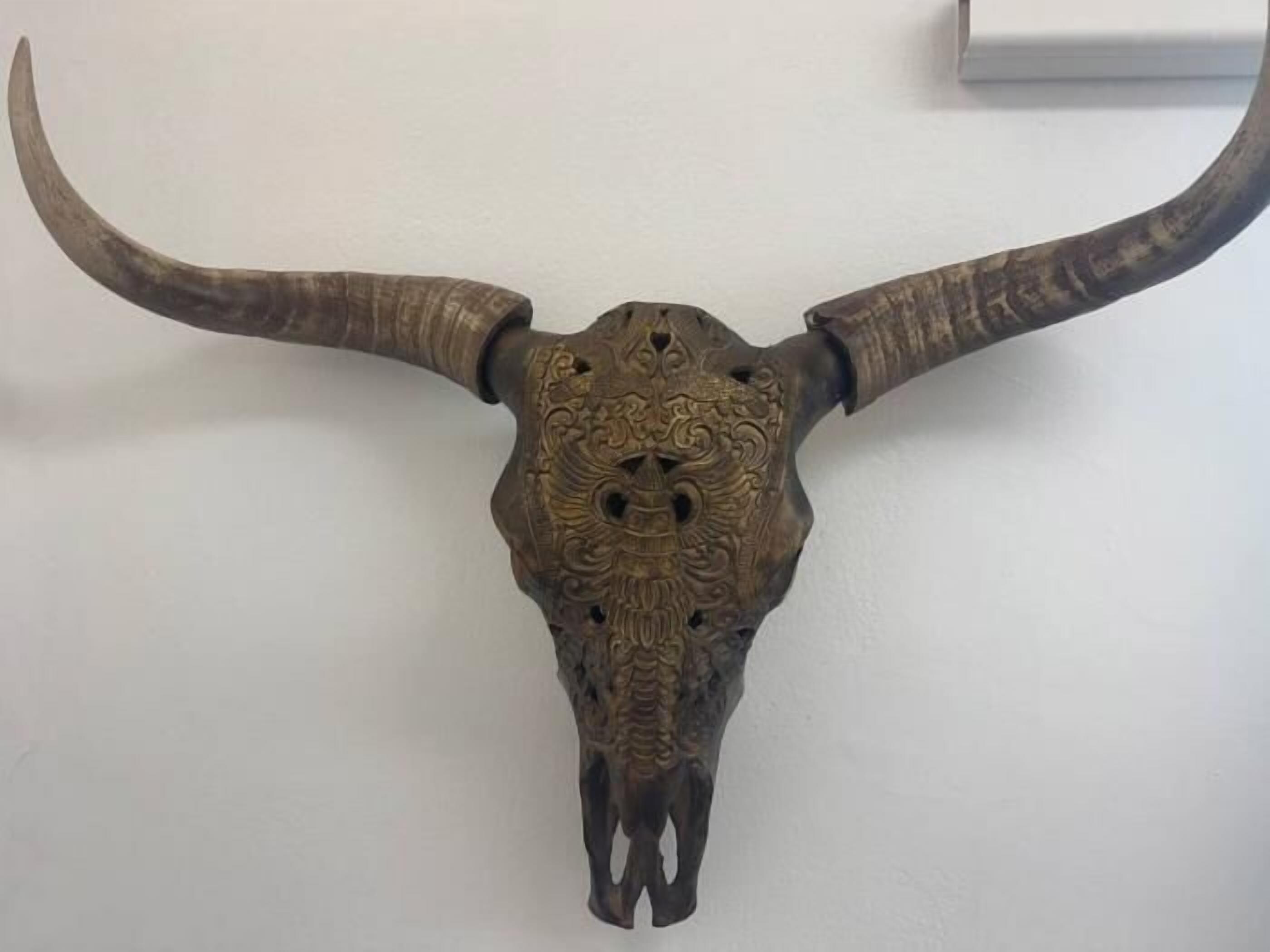 Un cráneo de toro grande y ornamentado montado en la pared.